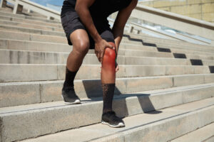 Close-up of a young man with a knee injury and signs of inflammation.