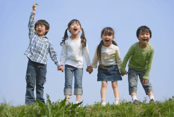 Children holding hands and happily laughing on a field